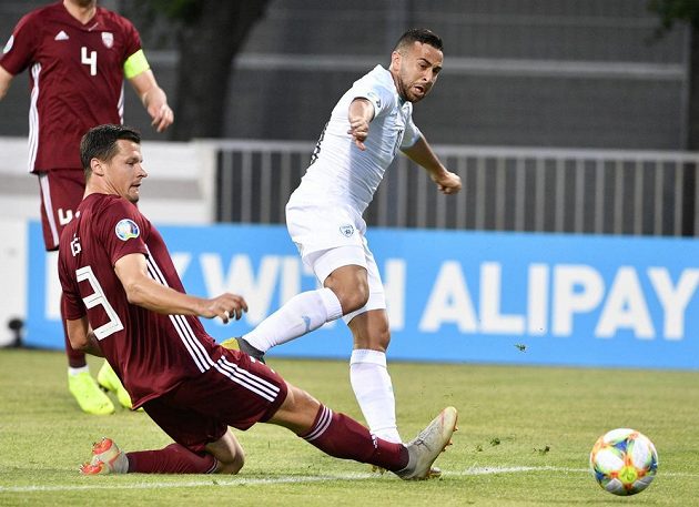 Lotyšský fotbalový reprezentant Marcis Oss se snaží zastavit míč, který odehrál Izraelec Dia Seba v utkání kvalifikace o postup na EURO 2020.