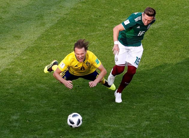 Švédský fotbalista Albin Ekdal padá po souboji s Mexičanem Hectorem Herrerou během utkání mistrovství světa.