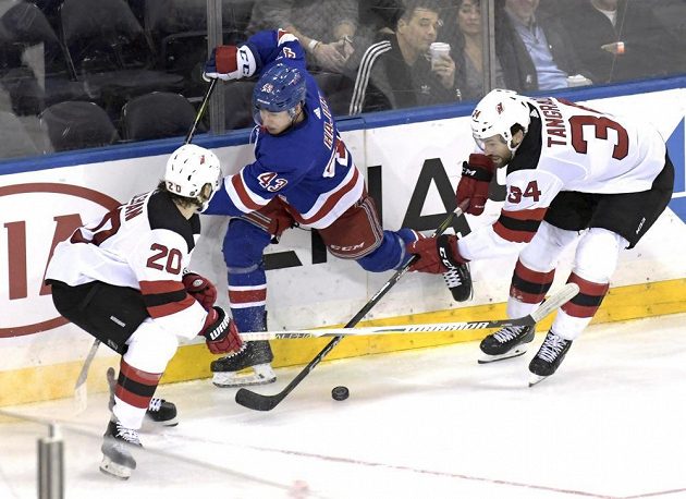 Český obránce NY Rangers Libor Hájek (v modrém) mezi Blakeam Colemanem (20) a Ericem Tangradim (34) během třetí třetiny utkání NHL mezi NY Rangers a New Jersey.