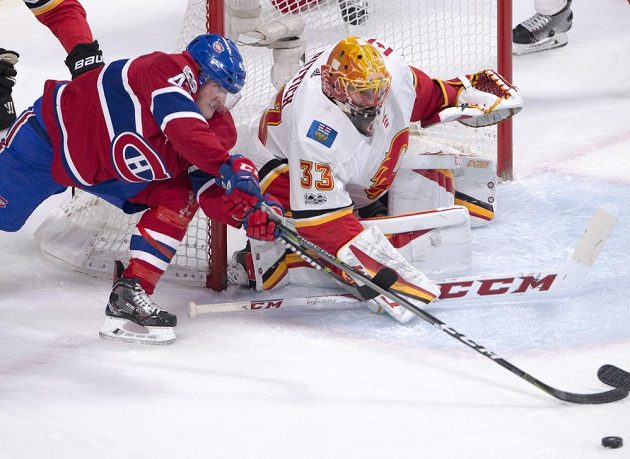 Útočník Montrealu Canadiens Daniel Carr se natahuje za pukem v utkání NHL proti Calgary, stejný záměr má i gólman Plamenů David Rittich.