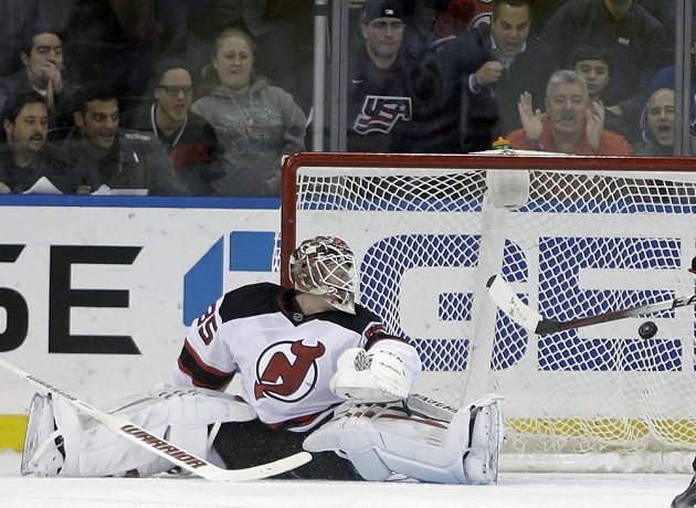 Brankář New Jersey Cory Schneider inkasuje gól z hole útočníka New Yorku Rangers Dereka Stepana.