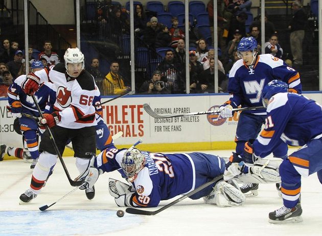 Jaromír Jágr (68)z New Jersey Devils v tomhle případě ještě brankáře New York Islanders Jevgenije Nabokova nepřekonal, bránit se snaží Kyle Okposo (21) a Travis Hamonic (3). O pár minut později se ale Jágr dočkal - dal svůj 700. gól v NHL
