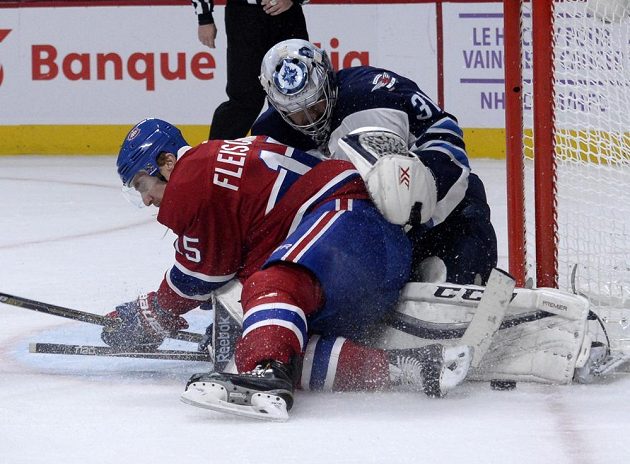 Gólman Winnipegu Ondřej Pavelec (31) zastavuje akci montrealského Tomáše Fleischmanna (15) ve třetí třetině.