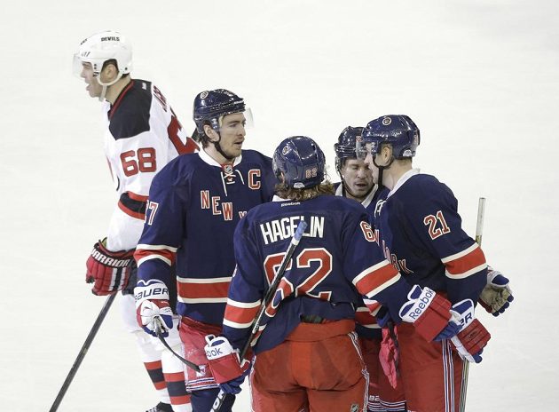 Útočník New Yorku Rangers Derek Stepan (zcela vpravo) slaví se spoluhráči gól proti New Jersey. Vlevo je zklamaný Jaromír Jágr.