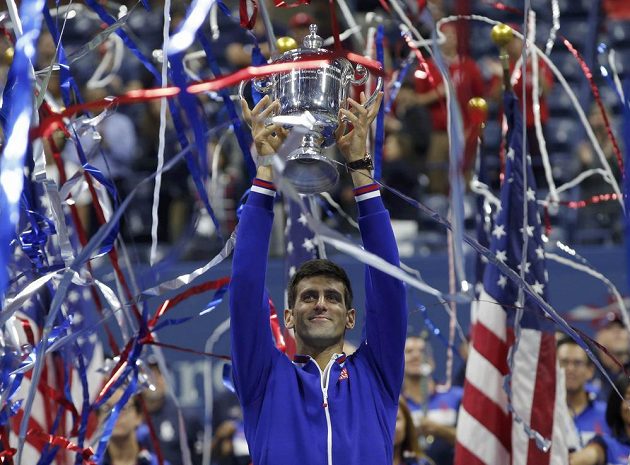 Světová tenisová jednička Novak Djokovič s trofejí pro šampióna US Open nad hlavou.