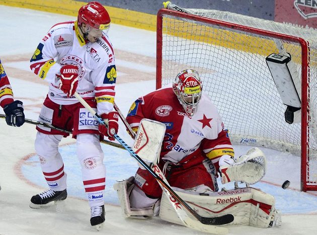 Třinecký útočník Tomáš Plíhal (vlevo) se snaží dopravit puk za záda slávistického brankáře Dominika Furcha v předehrávce 50. kola hokejové Tipsport extraligy.