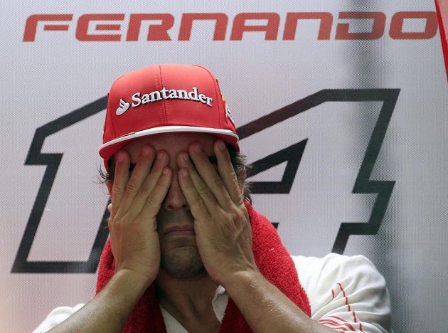 Pilot Ferrari Fernando Alonso stírá pot z obličeje při měřeném tréninku v Sepangu.