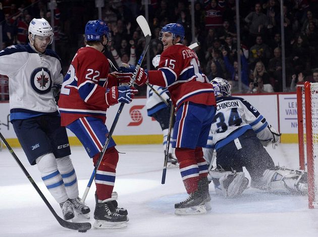 Montrealský Tomáš Fleischmann (15) a Dale Weise (22) se radují z gólu v první třetině, vlevo Adam Lowry z Winnipegu, vpravo překonaný brankář Michael Hutchinson (34).