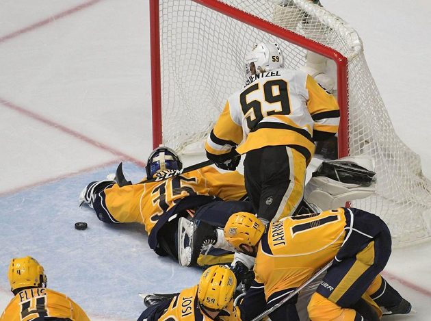 Gólman Nashvillu Pekka Rinne (35) zastavuje nejlepšího střelce play off NHL Jakea Guentzela (59).