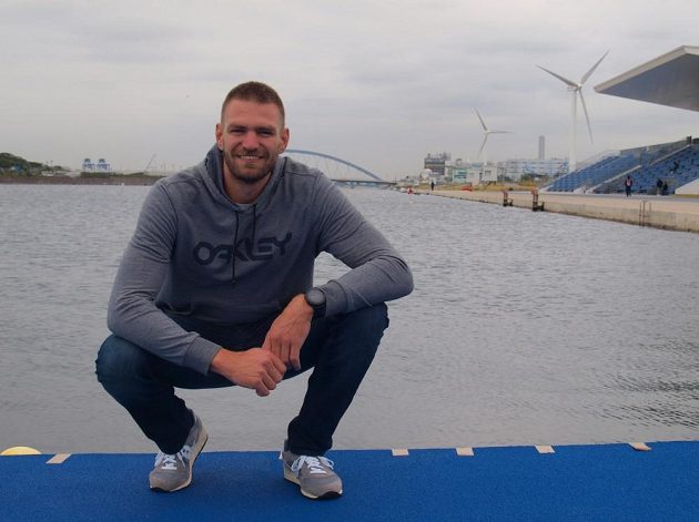 Skifař Ondřej Synek, za ním olympijský kanál v Tokiu i s větrnými turbínami.