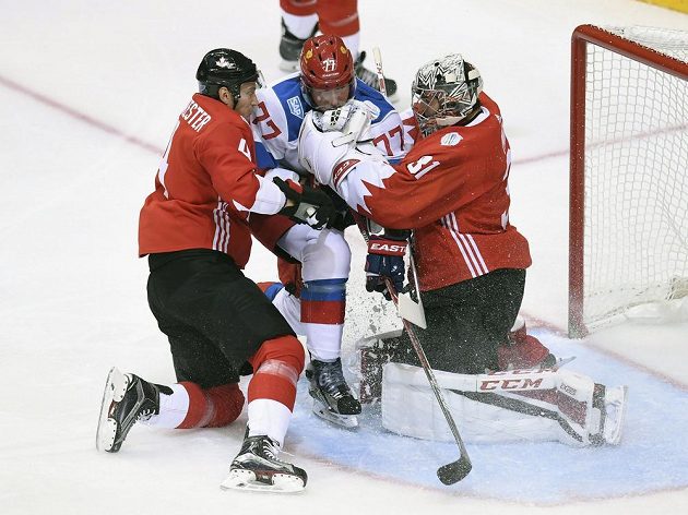 Mela před brankářem Kanady Carey Pricem (31) mezi Ivanem Těleginem (77) z Ruska a Jayem Bouwmeesterem (4).