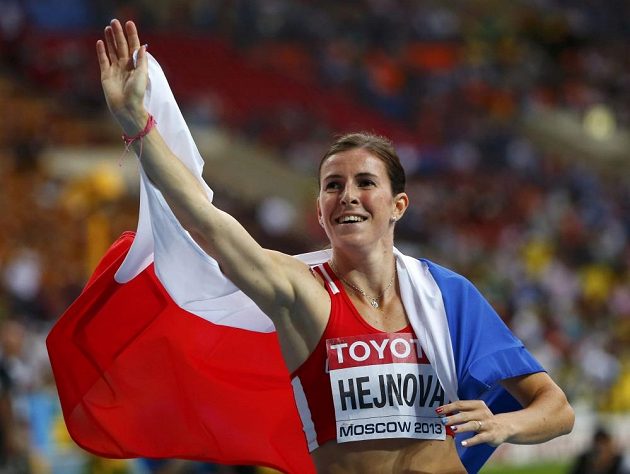 Zuzana Hejnová s českou vlajkou zdraví fanoušky po triumfu ve finále na 400 m překážek na MS v Moskvě.