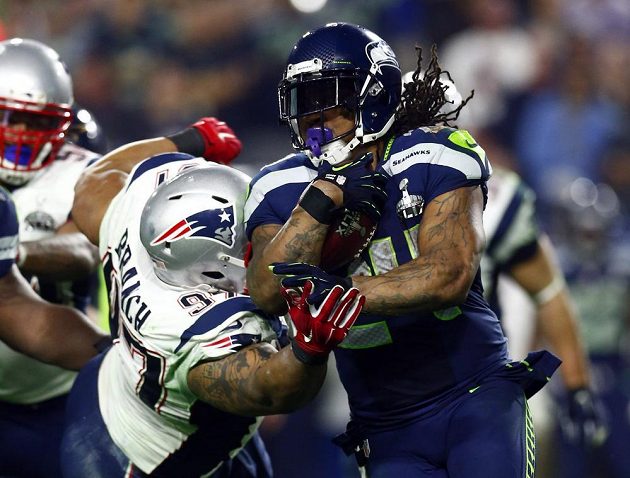 Tvrdý souboj Marshawna Lynche (vpravo) s Alanem Branchem z New England Patriots.