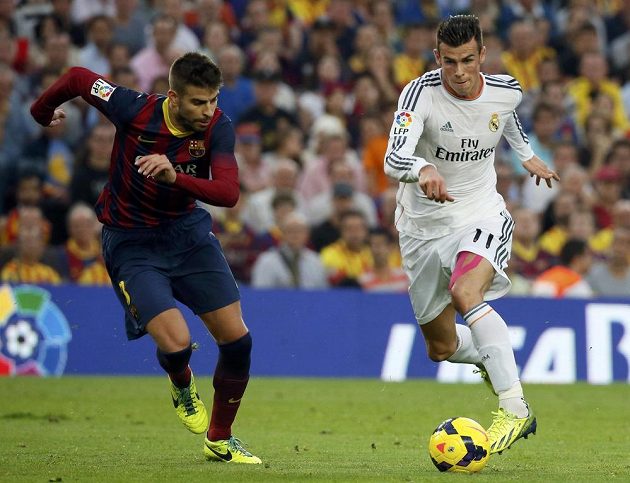 Hvězda Realu Gareth Bale (v bílém) ve sprinterském souboji s obráncem Barcelony Gerardem Piquém.