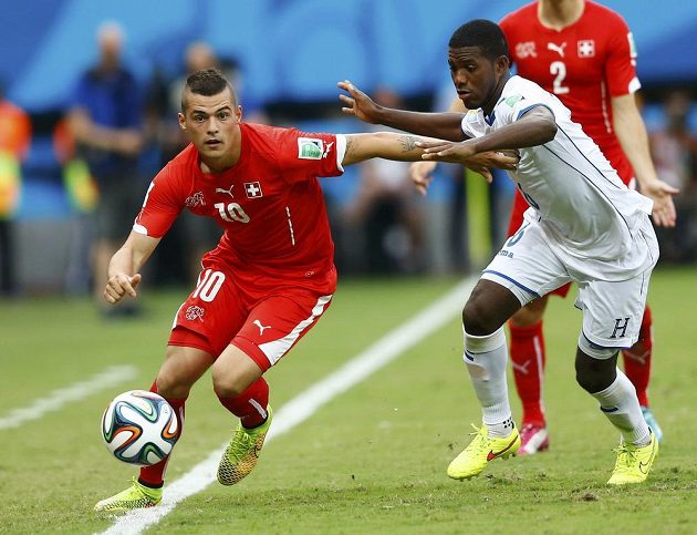 Švýcar Granit Xhaka (vlevo) se zkouší prosmýknout kolem bránícího Juana Carlose Garcíu z Hondurasu.