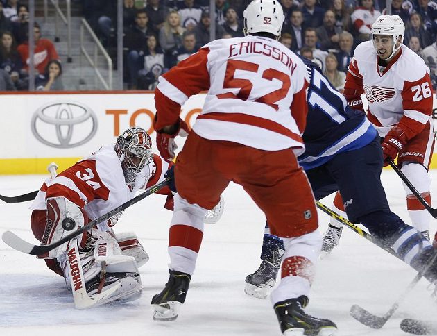 Adam Lowry (č. 17) z Winnipegu překonává brankáře Detroitu Petra Mrázka. Přihlížejí obránce Red Wings Jonathan Ericsson a útočník Tomáš Jurčo (vpravo).