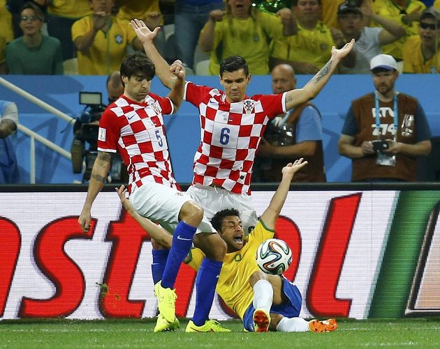 Brazilec Fred (ve žlutém dresu) se ocitá na zemi po souboji s obráncem Dejanem Lovrenem (vpravo).
