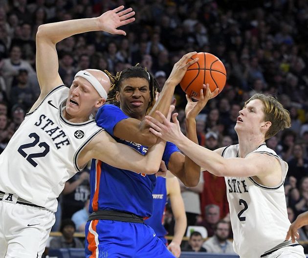 Derrick Alston z Boise State (uprostřed) se snaží dostat ke střele mezi dvěma hráči Utahu.
