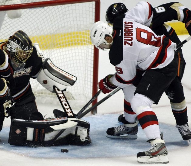 Gólman Kačerů Jonas Hiller zasahuje před dorážejícím Daniusem Zabrusem z New Jersey.
