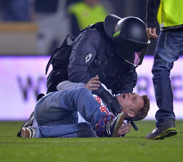 Policejní těžkooděnci zasahují proti fanouškům Slavie, kteří po skončení zápasu vnikli na hřiště.