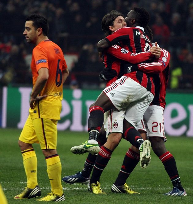 Sulley Muntari (vpravo) se raduje se svými spoluhráči z AC Milán z gólu. Vpravo smutný Xavi z Barcelony.