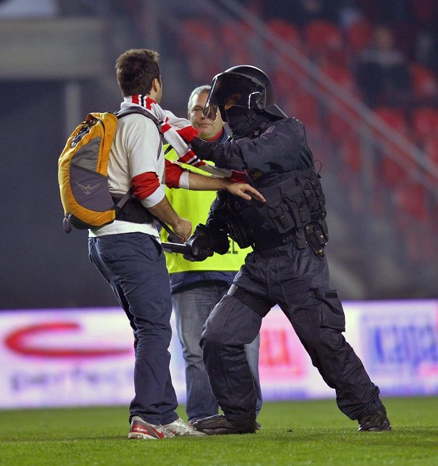 Policejní těžkooděnci zasahují proti fanouškům Slavie, kteří po skončení zápasu vnikli na hřiště.
