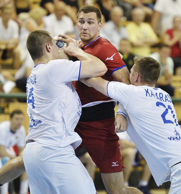 Český hráč Tomáš Babák se snaží prosadit mezi Dmitrijem Santalovem (vlevo) a Glebem Kalarašem z Ruska v úvodním utkání play off kvalifikace mistrovství světa házenkářů.
