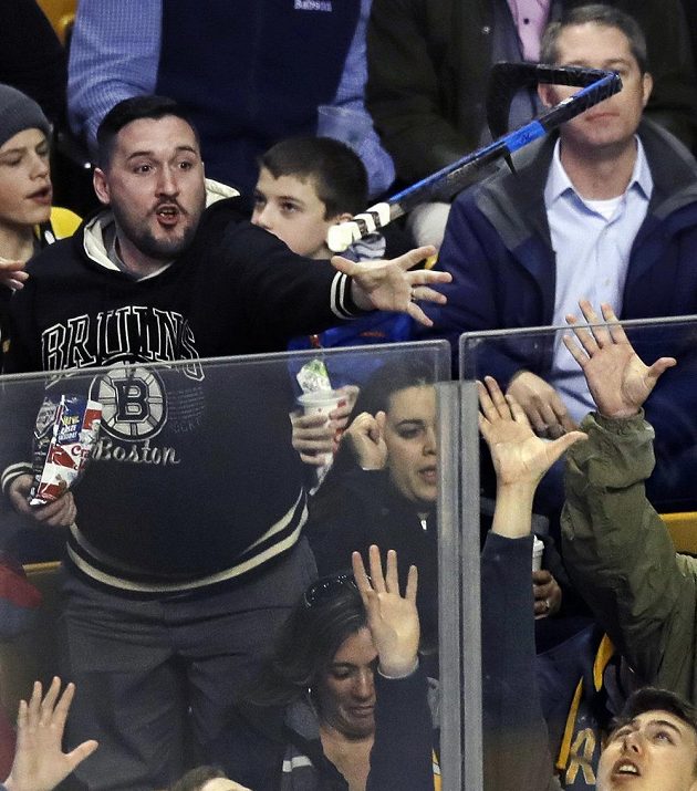 Fanoušek Bostonu chytá hokejku, kterou vhodil do hlediště útočník Bruins David Pastrňák poté, co překonal krajana v brance Detroitu Petra Mrázka.