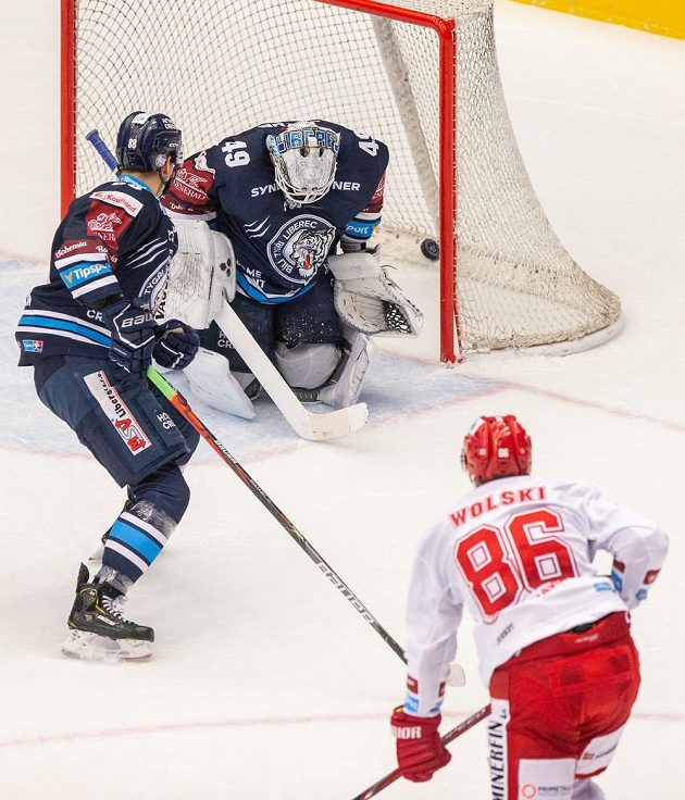 Liberecký hokejista Michal Bulíř sleduje, jak zasahuje v brance jeho spoluhráč Dominik Hrachovina. Všemu přihlíží Wojciech Wolski z Třince.