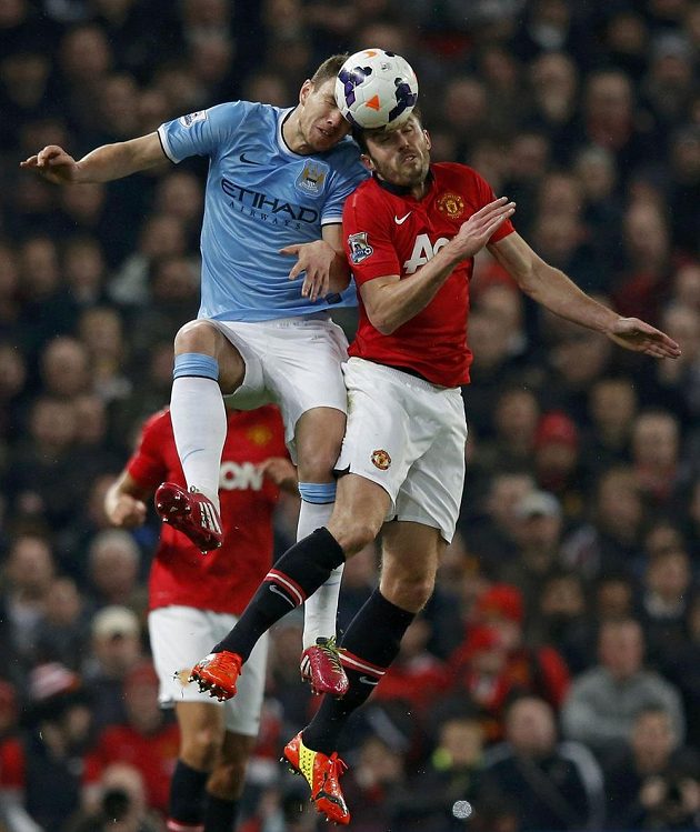 Střelec úvodního gólu derby Edin Džeko (vlevo) z Manchesteru City v hlavičkovém souboji s Michaelem Carrickem z United.