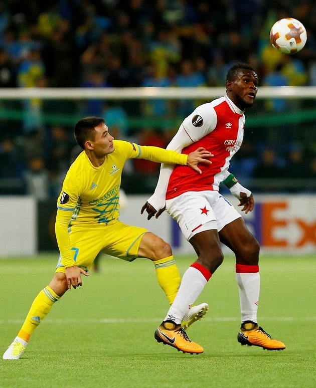 Fotbalista Slavie Michael Ngadeu-Ngadjui se chystá odehrát míč v utkání Evropské ligy na hřišti Astany. Atakovat se hráče Slavie chystá domácí Serikžan Mužikov.