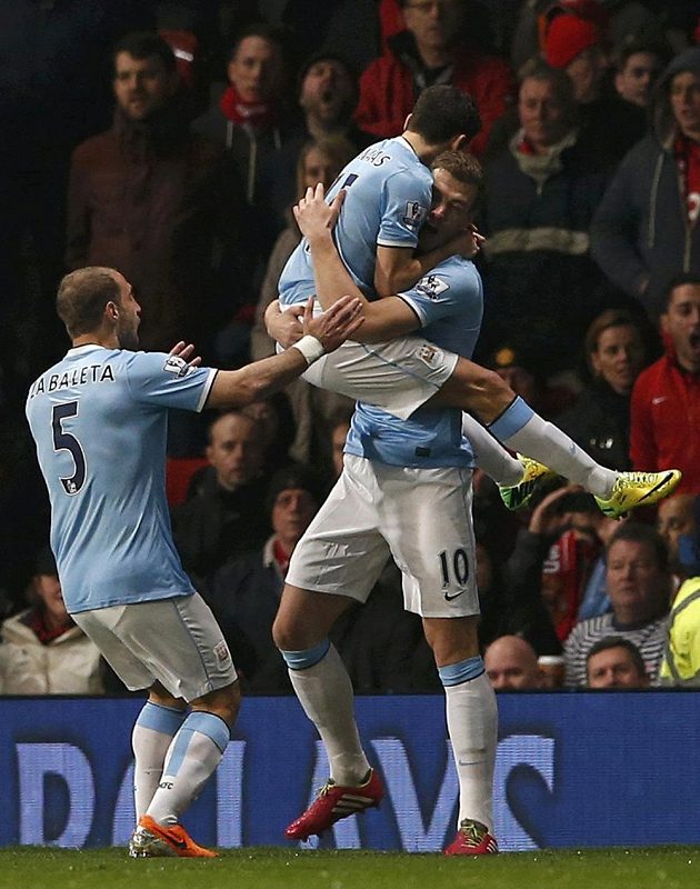 Fotbalisté Manchesteru City Edin Džeko (vpravo) a Jesús Navas se radují ze vstřelení gólu proti Manchesteru United. Vlevo přibíhá spoluhráč Pablo Zabaleta.