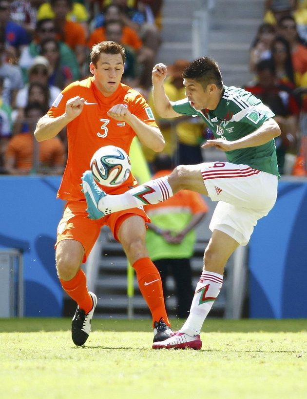 Mexický forvard Oribe Peralta (vpravo) odehrává míč před Stefanem de Vrijem z Nizozemska.