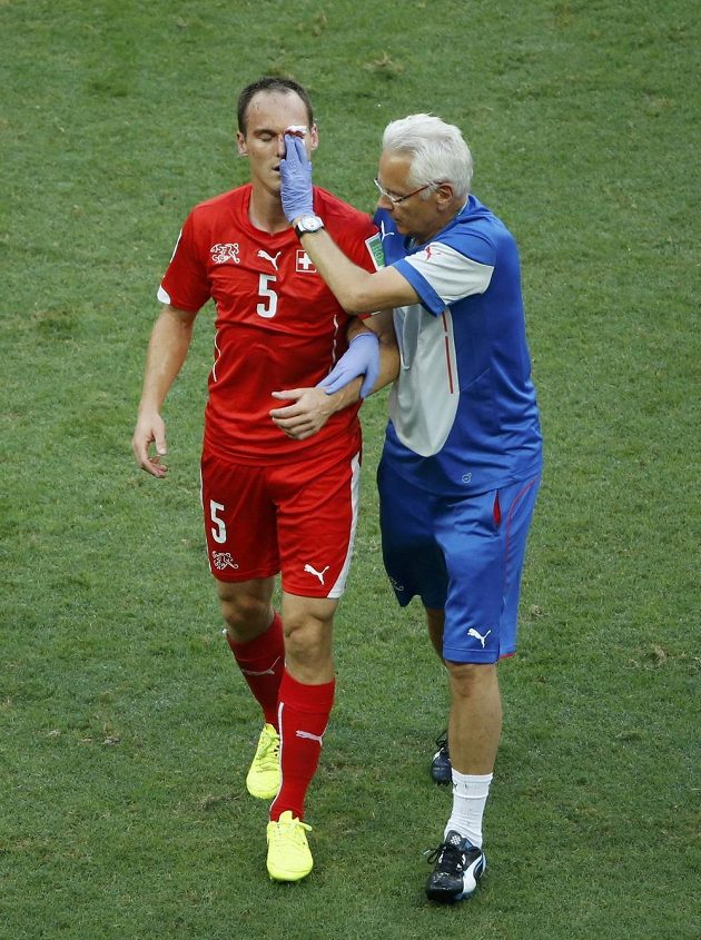 Zraněný švýcarský obránce Steve von Bergen opouští trávník v doprovodu lékaře.