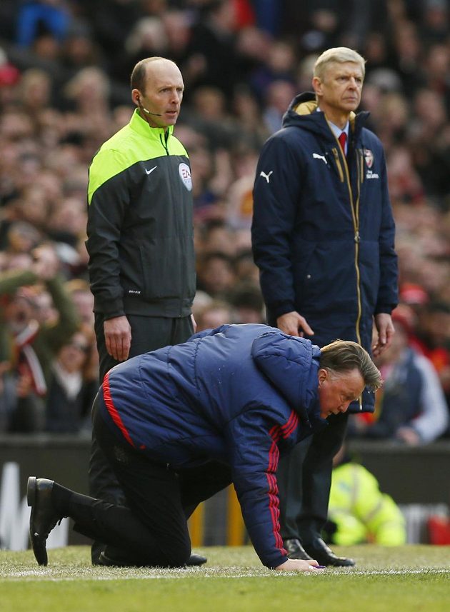 Kouč Manchesteru United Louis van Gaal se ztěžka zvedá, za ním vlevo je čtvrtý rozhodčí Mike Dean a trenér Arsenalu Arséne Wenger.