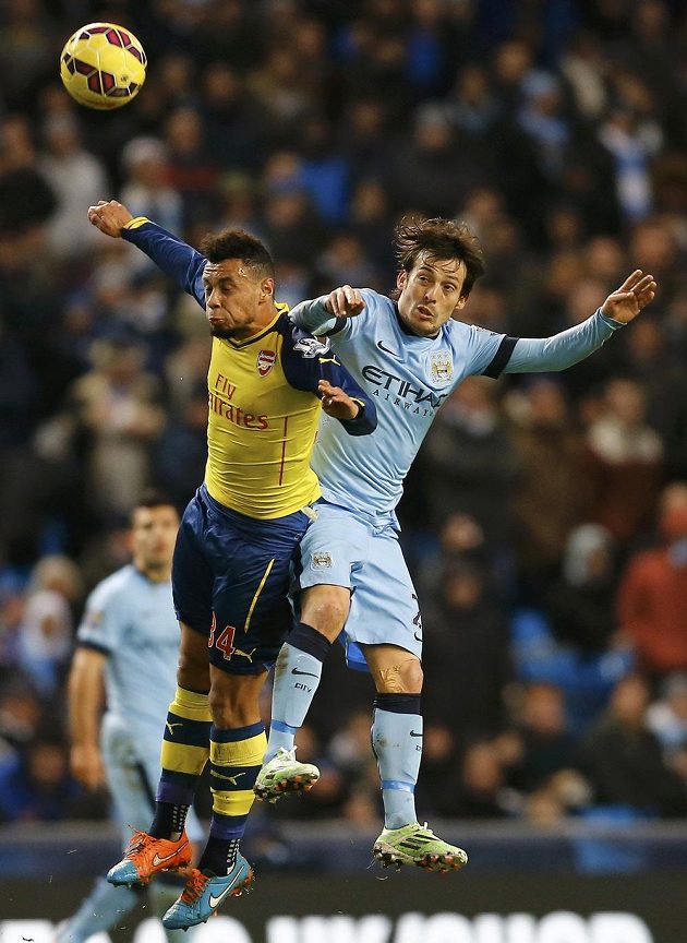 Záložník Arsenalu Francis Coquelin ve vzdušném souboji s Davidem Silvou z Manchesteru City.