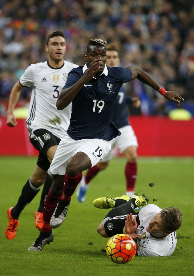 Z přípravy Francie - Německo v Paříži. Domácí středopolař Paul Pogba obchází ležícího Bastiana Schweinsteigera.