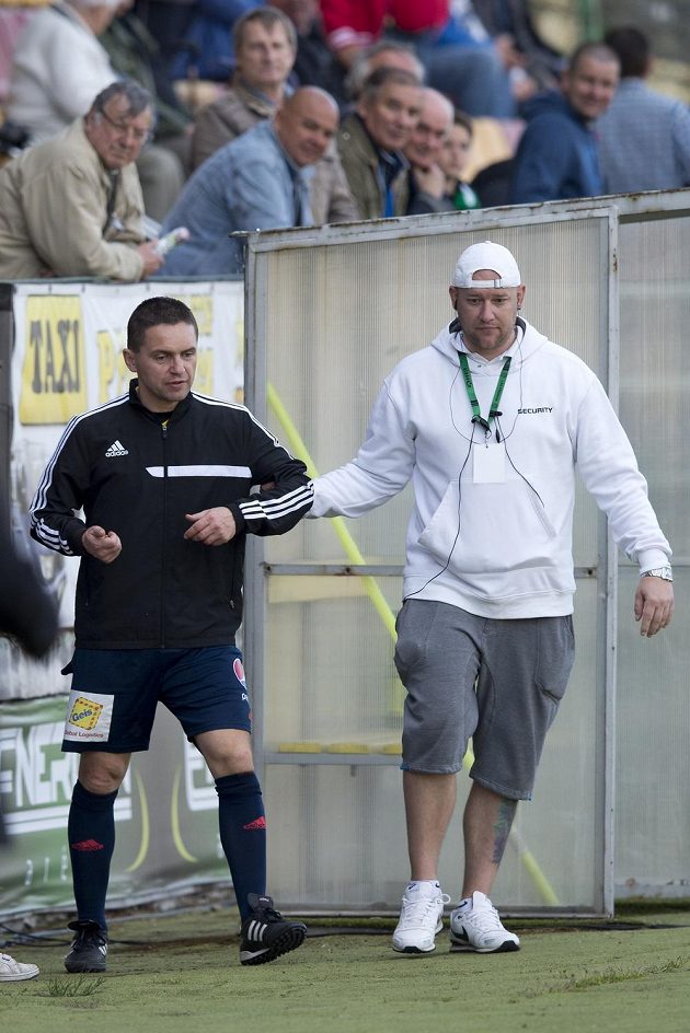 Pořadatel v přestávce vyvádí ze hřiště čtvrtého rozhodčího Marka Pilného (vlevo), který byl při ligovém duelu v Příbrami pod vlivem alkoholu.