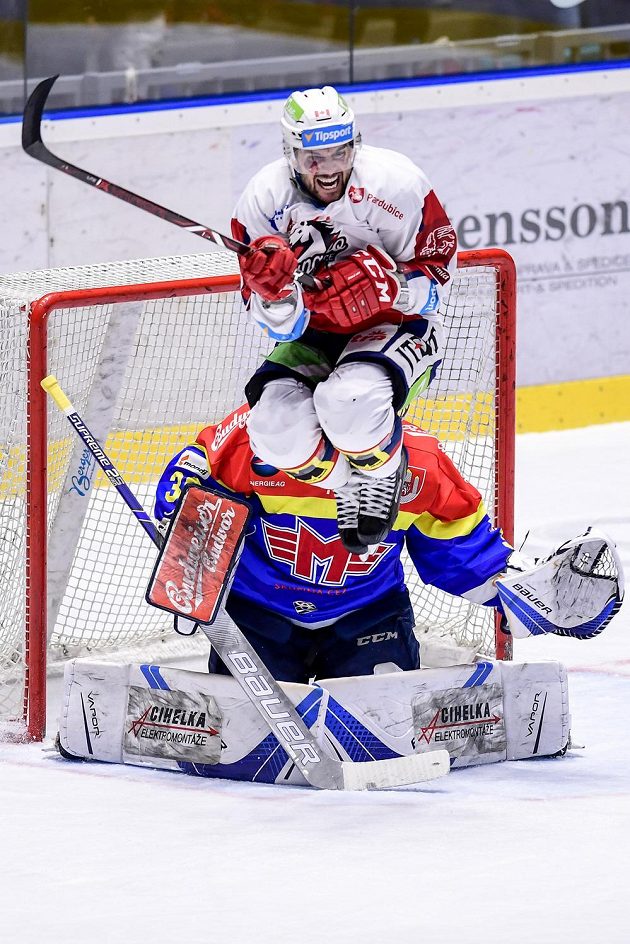 Brian Ihnačák (ve výskoku) z Pardubic a brankář Budějovic Petr Kváča během utkání baráže o hokejovou extraligu.
