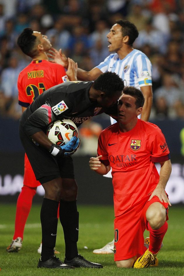 Zatímco brankář Málagy Carlos Kameni zvedá z trávníku Lionela Messiho, obránce Weligton Oliveira v pozadí atakuje dalšího útočníka Barcelony Munira El Haddadiho.