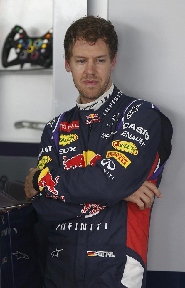Zamyšlený Sebastian Vettel vyčkává v garáži Red Bullu při měřeném tréninku v Sepangu.