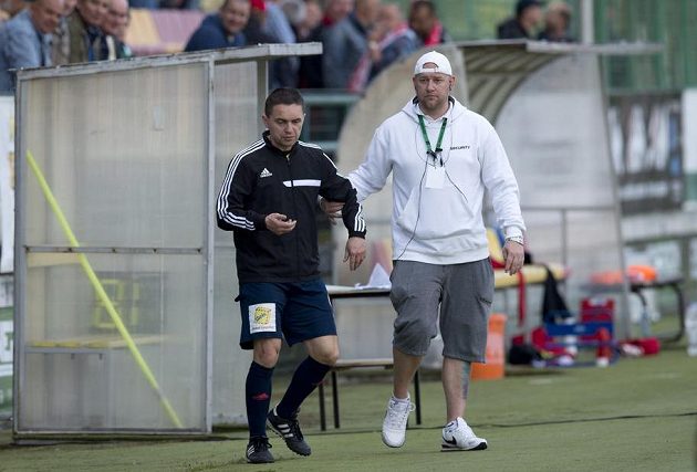 Pořadatel v přestávce vyvádí ze hřiště čtvrtého rozhodčího Marka Pilného (vlevo), který byl při ligovém duelu Příbram - Slavia pod vlivem alkoholu.