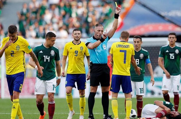 Hlavní rozhodčí uděluje žlutou kartu švédskému fotbalistovi Sebastianu Larsonovi v utkání mistrovství světa proti Mexiku.
