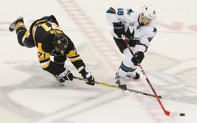 Tomáš Hertl vyváží kotouč před padajícím útočníkem Jevgenijem Malkinem z Pittsburghu.