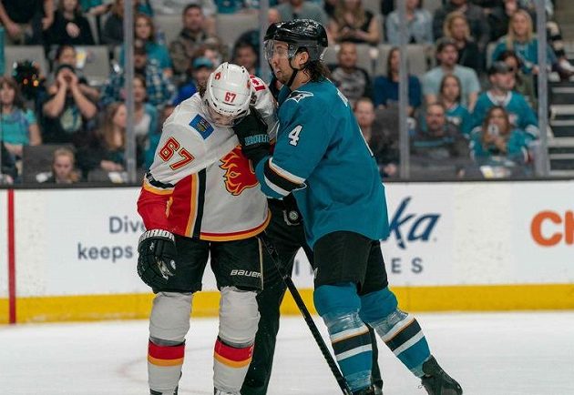Český útočník Calgary Flames Michael Frolík čelí útoku obránce San Jose Sharks Brendena Dillona (4) během utkání NHL.