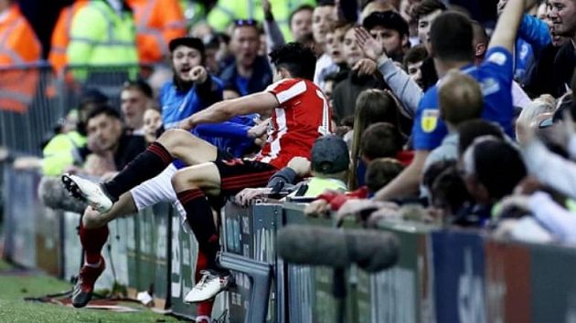 Fanoušek Portsmouthu nakopl hostujícího fotbalistu Sunderlandu Luka O’Niena během utkání playoff třetí anglické ligy. Fanoušek Portsmouthu nakopl hostujícího fotbalistu Sunderlandu Luka O’Niena během utkání playoff třetí anglické ligy.