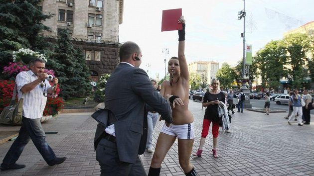 Pracovník ochranky odvádí protestující obnaženou dívku, která se snažila narušit ceremoniál k odpočítávání začátku Eura 2012. Pracovník ochranky odvádí protestující obnaženou dívku, která se snažila narušit ceremoniál k odpočítávání začátku Eura 2012.