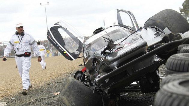 Bezpečnostní pracovník si prohlíží vrak Audi R18 TDI britského pilota Allana Mcnishe. Bezpečnostní pracovník si prohlíží vrak Audi R18 TDI britského pilota Allana Mcnishe.
