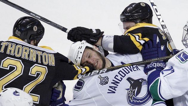 Obránce Vancouveru Kevin Bieksa v sevření hráčů Bostonu Obránce Vancouveru Kevin Bieksa v sevření hráčů Bostonu
