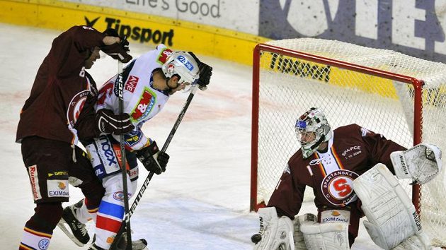 Brankář Sparty Petr Přikryl chytá střelu Radovana Somíka z Pardubic (uprostřed), kterého brání René Vydarený. Brankář Sparty Petr Přikryl chytá střelu Radovana Somíka z Pardubic (uprostřed), kterého brání René Vydarený.